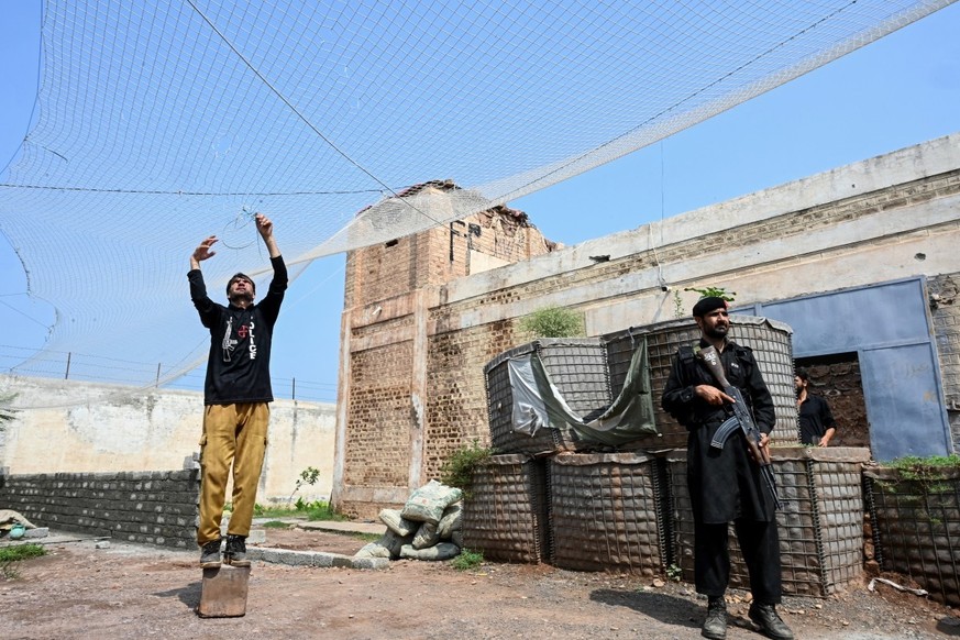 This photograph taken on August 4, 2026 shows security personnel fortifying a police post with Ukraine-style mesh barriers, as a new line of defence against militant drone and aerial attacks at Bara i ...