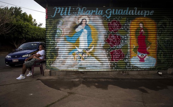 epa09628504 A man is seen near a mural of the virgin Mary during the start of the festivities for the celebration of La Purisima in Managua, Nicaragua, 07 December 2021. Nicaragua celebrated this Tues ...