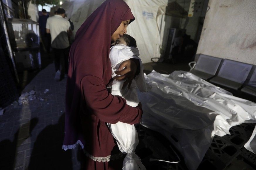 A Palestinian woman mourns her relative, 7-month old baby Hani Qeshta, who was killed in an Israeli bombardment on a residential building with Qeshta&#039;s family, at the morgue of Al Najjar hospital ...