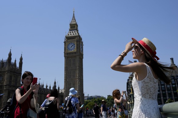Tourists pose for photographs on Westminster Bridge in London, Tuesday, July 19, 2022. Millions of people in Britain woke from the country's warmest-ever night on Tuesday and braced for a day whe ...