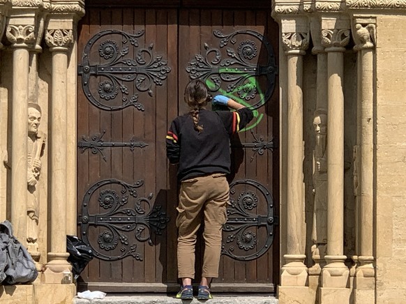 Nettoyage de ce qui ressemble à une «croix sataniste». L'une des portes de la collégiale de Neuchâtel.