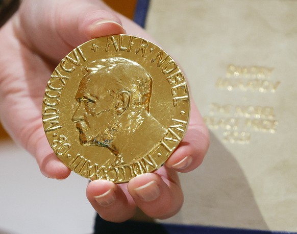 epa10024632 The 2021 Nobel Peace Prize is held by a handler before the start of an auction benefiting Ukrainian children, at The Times Center in New York, New York, USA, 20 June 2002. The 2021 Nobel P ...