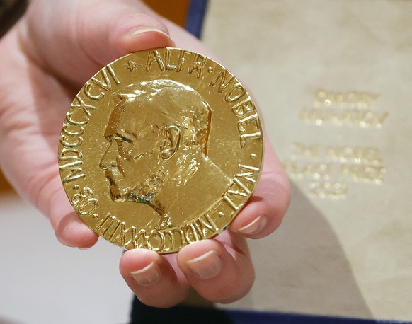 epa10024632 The 2021 Nobel Peace Prize is held by a handler before the start of an auction benefiting Ukrainian children, at The Times Center in New York, New York, USA, 20 June 2002. The 2021 Nobel P ...