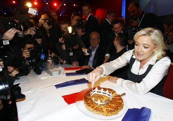 French far-right leader Marine Le Pen and National Front Party candidate for the 2012 French presidential elections, right, shows the traditional Twelfth night cake during a meeting in Saint Denis, no ...