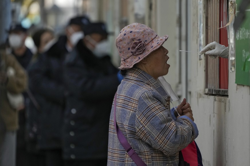 A woman takes off her mask to have her throat swabbed for a COVID-19 test at a coronavirus testing site in Beijing, Wednesday, Nov. 23, 2022. The ruling Communist Party promised earlier this month to  ...