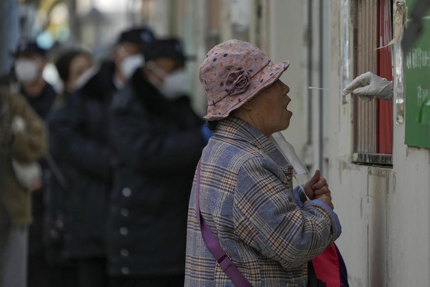 Une femme enlève son masque pour subir un test de Covid-19 à Pékin.