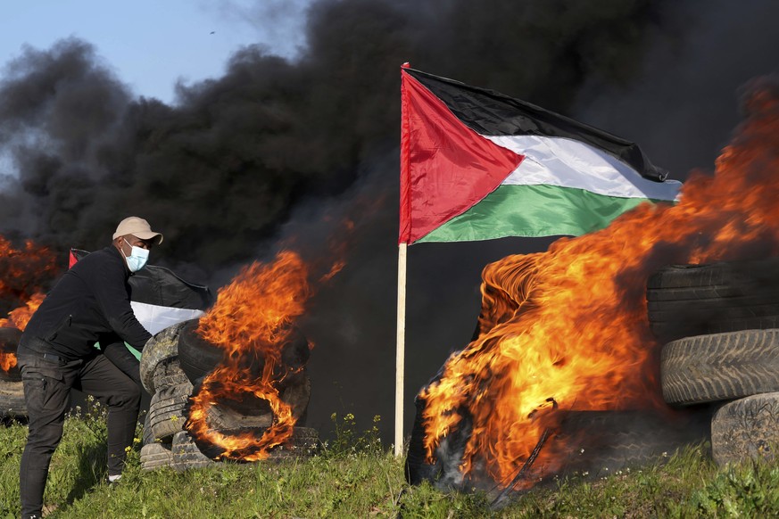 A demonstrator adds burning tires during a protest against Israeli military raid in the West Bank city of Nablus, along the border fence with Israel, in east of Gaza City, Wednesday, Feb. 22, 2023. Pa ...