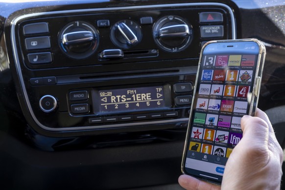 Une personne regarde sont smartphone ou s&#039;affiche les stations de radio suisse vers l&#039; autoradio de sa voiture, ce mercredi 4 decembre 2024 a Geneve. La SSR va mettre fin a la diffusion FM d ...