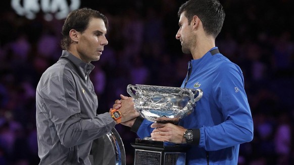 Serbia&#039;s Novak Djokovic, right, shakes hands with Spain&#039;s Rafael Nadal as they hold their trophies after Djokovic won the men&#039;s singles final at the Australian Open tennis championships ...