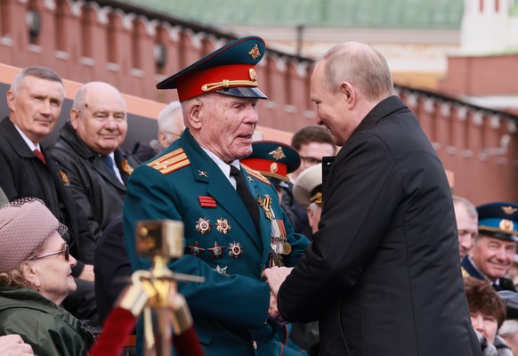 epa09935185 Russian President Vladimir Putin (R) shakes hands with a military veteran prior to the Victory Day military parade in the Red Square in Moscow, Russia, 09 May 2022. The Victory Day militar ...