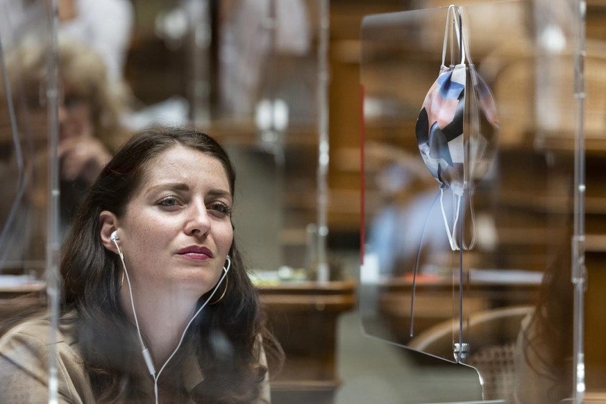 Leonore Porchet, GP-VD, hoert einem Votum zu, ihre Schutzmaske haengt an der Plexiglasscheibe, an der Herbstsession der Eidgenoessischen Raete, am Mittwoch, 9. September 2020 im Nationalrat in Bern. A ...