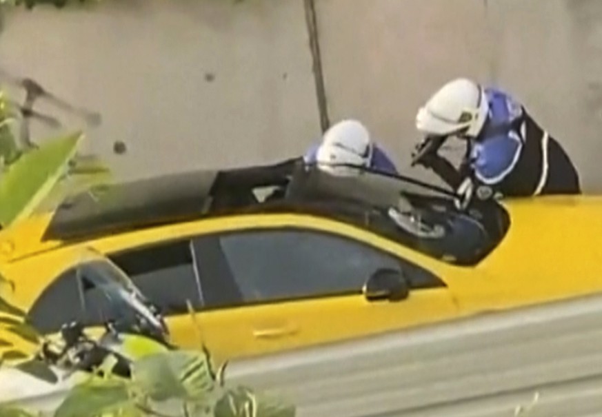 In this grab taken from video provided by @Ohana_FNG, two police officers question a driver, one pointing a gun towards the window of a yellow car, in Nanterre, France, Tuesday, June 27, 2023. France? ...
