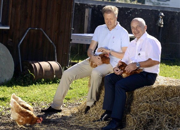 Bundesrat Ueli Maurer, rechts, mit Migros CEO Herbert Bolliger, links, und Huehnern bei einem Brunch auf einem Bauernhof in Uetikon am See (ZH) am 1. August 2012. (KEYSTONE/Walter Bieri)
