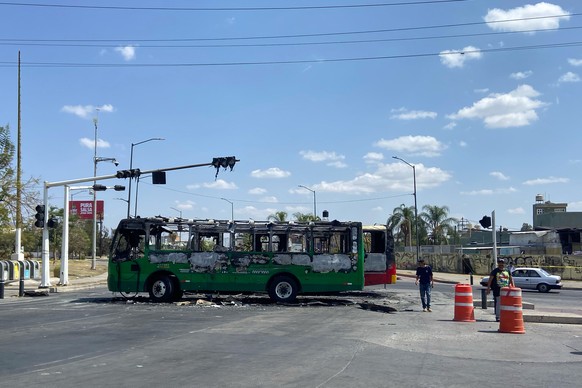 Pedestrians walk past charred buses that were set on fire, on a road in Guadalajara, Jalisco state, Mexico, Sunday, Feb. 22, 2026, after the death of the leader of the Jalisco New Generation Cartel, N ...