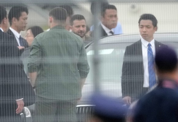 epa10639958 Ukrainian President Volodymyr Zelensky (C) is seen through a fence as he arrives at the Hiroshima airport to attend the G7 Hiroshima Summit in Hiroshima, Japan, 20 May 2023. The G7 Hiroshi ...