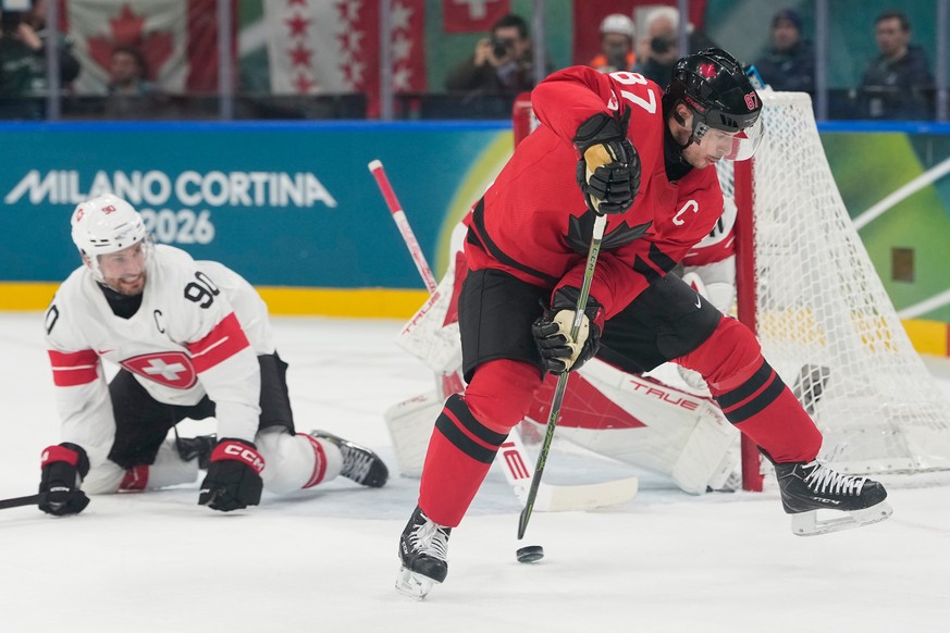 Canada's Sidney Crosby passes the puck during a preliminary round match of men's ice hockey between Canada and Switzerland at the 2026 Winter Olympics, in Milan, Italy, Friday, Feb. 13, 2026 ...