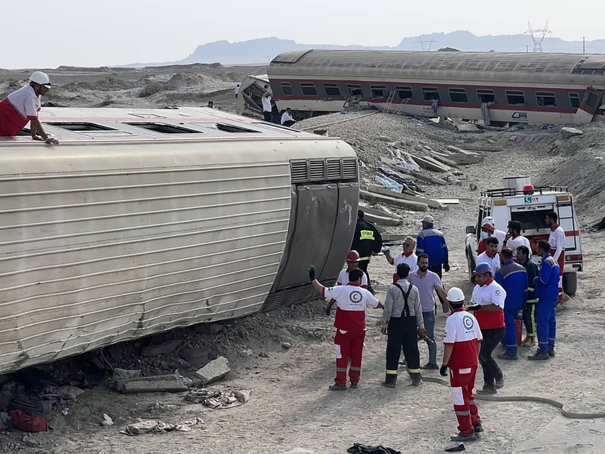 In this photo provided by Iranian Red Crescent Society, rescuers work at the scene where a passenger train partially derailed near the desert city of Tabas in eastern Iran, Wednesday, June 8, 2022. (I ...