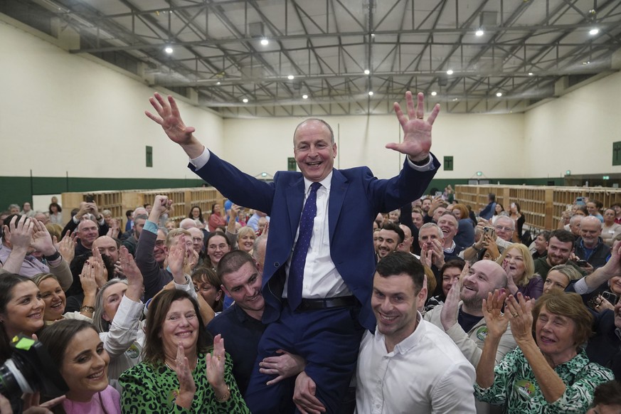 Fianna Fail leader Micheal Martin is hoisted up by his sons Cillian and Micheal Aodh, after he was deemed elected in the Cork South Central constituency at the election count centre at Nemo Rangers GA ...