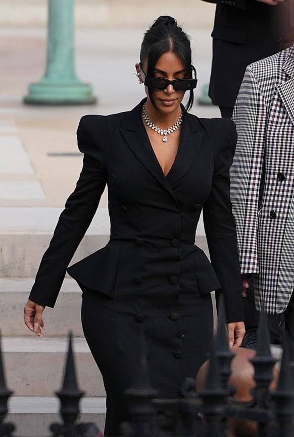 PARIS, FRANCE - MAY 13: Kim Kardashian exits the trial at the Palais de Justice, and wears sunglasses by Alaia, a black dress designed as a double breasted gathered blazer jacket with power shoulders  ...