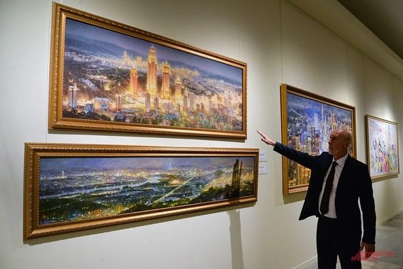 Un employé du musée parle de la peinture « Illumination nocturne de la rue Chonvi », réalisée selon la technique du posok-hwa, inventée en RPDC, qui consiste à utiliser de la poudre de pierres semi-pr ...