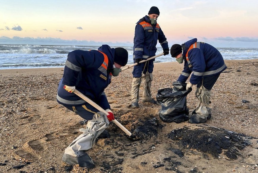 epa11783933 A handout image released by the press service of the Russian Ministry of Emergency Situations shows, employees of the Russian Ministry of Emergency Situations collecting oil-soaked beach s ...