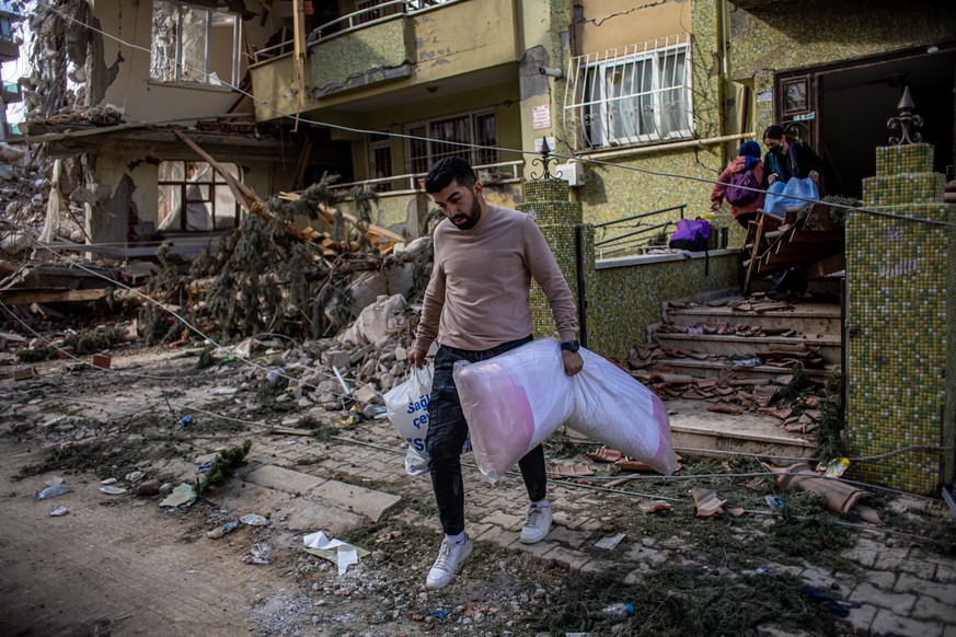Un homme sort ses affaires hors d'une maison endommagée par le puissant séisme, à Hatay, en Turquie.