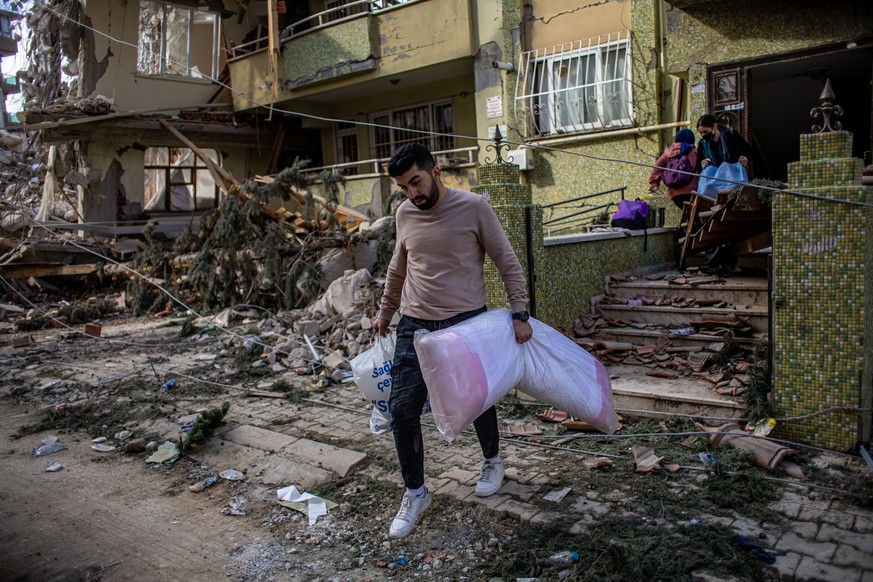 epa10478184 A man carries belongings out of a damaged house after a powerful earthquake, in Hatay, Turkey, 19 February 2023. More than 46,000 people have died and thousands more are injured after two  ...