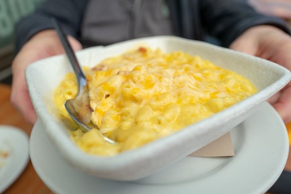 Close-up of plate of Peruvian macaroni and cheese with bacon, with man&#039;s hands visible in background, at Parada restaurant in Walnut Creek, California, March 4, 2021. (Photo by Smith Collection/G ...