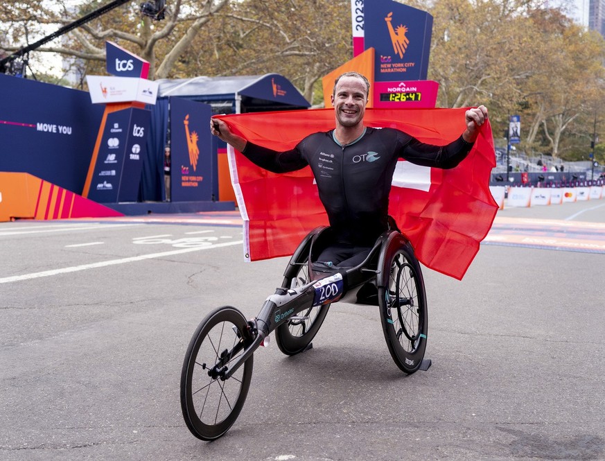Marcel Hug of Switzerland displays his country&#039;s flag after finishing first in the men&#039;s wheelchair division of the New York City Marathon, Sunday, Nov. 5, 2023, in New York.(AP Photo/Craig  ...