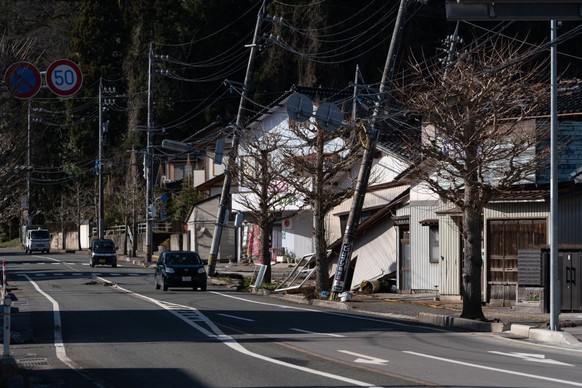 SUZU, JAPAN - JANUARY 04: Vehicles drive past damaged houses in the aftermath of an earthquake on New Year&#039;s Day on January 04, 2024 in Suzu, Japan. A series of major earthquakes have reportedly  ...