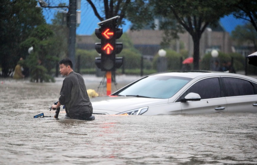 epa09356177 A man walks in the flooded road after record downpours in Zhengzhou city in central China&#039;s Henan province Tuesday, July 20, 2021 (issued 21 July 2021). Heavy floods in Central China  ...