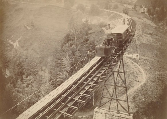 Une rame de la ligne Vitznau-Rigi circule sur le Schnurtobelbrücke vers 1875. La crémaillère du «système Riggenbach» est bien visible. Une personne précédait le train afin d’avertir le conducteur de t ...