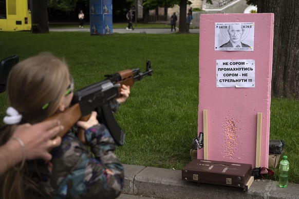 Victoria, 7 ans, utilise un fusil Kalachnikov en plastique pour tirer des balles sur un portrait du président russe Vladimir Poutine, lors d&#039;une attraction de rue dans le centre de Lviv, en Ukrai ...