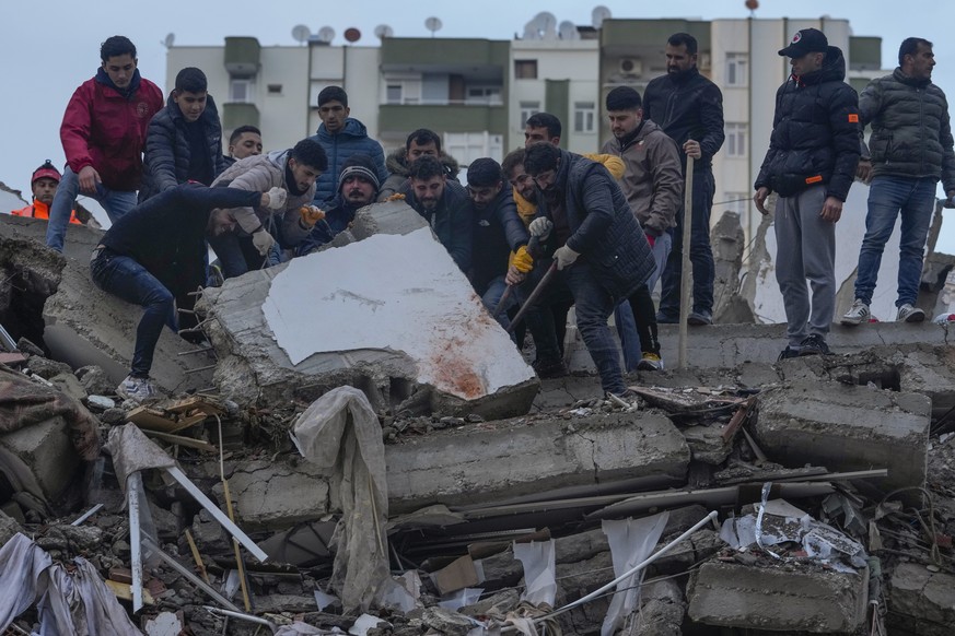Men search for people among the debris in a destroyed building in Adana, Turkey, Monday, Feb. 6, 2023. A powerful quake has knocked down multiple buildings in southeast Turkey and Syria and many casua ...