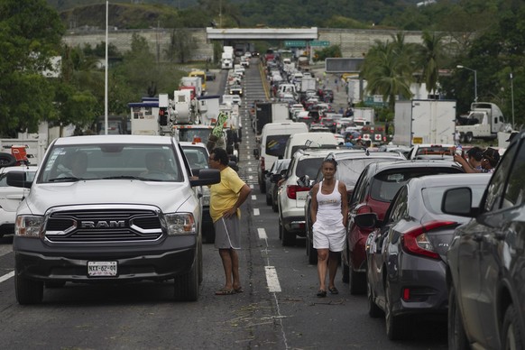 Des personnes attendent à l'extérieur de leur voiture que les équipes de réparation dégagent les routes après le passage de l'ouragan Otis.