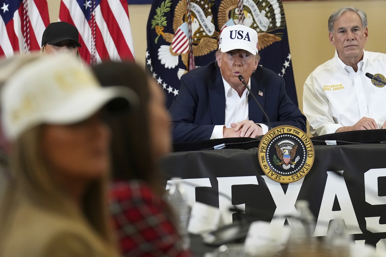 President Donald Trump speaks as Texas Gov. Greg Abbott, right, listens during a roundtable discussion with first responders and local officials at Hill Country Youth Event Center in Kerrville, Texas, ...