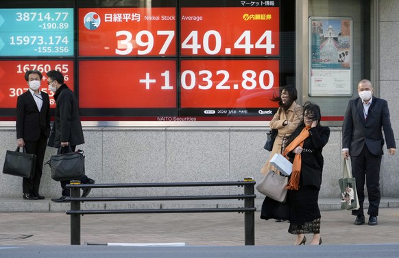 epa11227567 People stand in front of a stock market indicator board in Tokyo, Japan, 18 March 2024. Tokyo stocks rebounded sharply gaining more than two percent on export-related companies such as aut ...