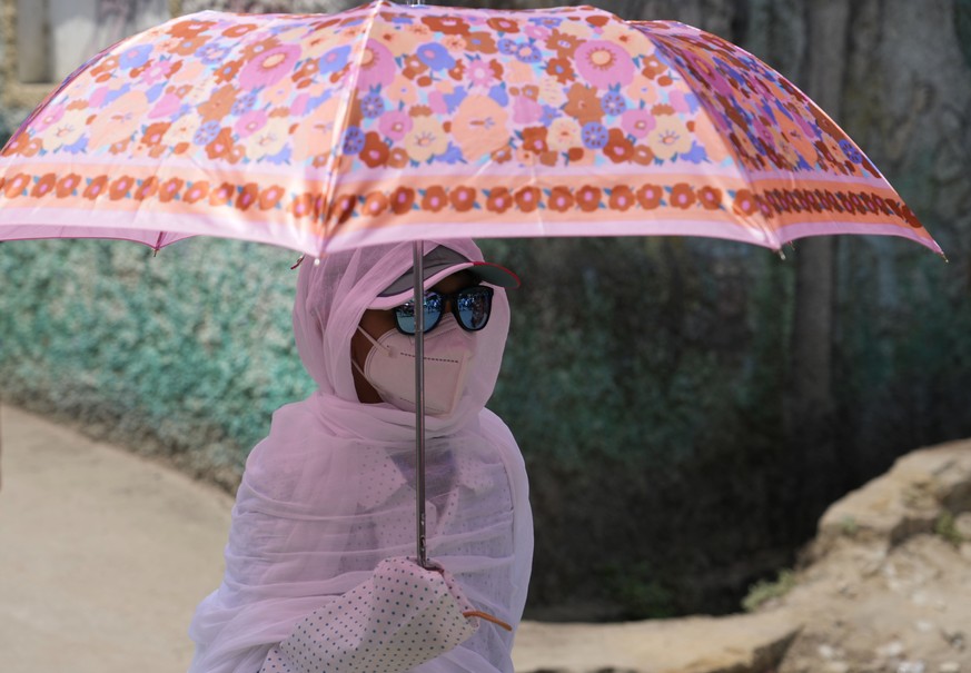 A schoolgirl holds an umbrella and covers herself with a scarf as protection from the sun in Prayagraj, in the northern Indian state of Uttar Pradesh, India, Thursday, April 21, 2022. Many parts of no ...