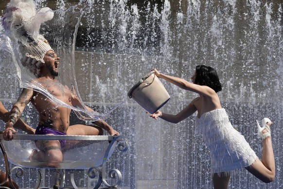 Members of the 'Australian cabaret and Circus troupe cool down in a fountain on the Southbank in London, Tuesday, July 19, 2022. Britain shattered its record for highest temperature ever register ...