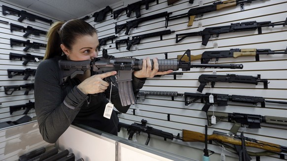 Gun shop owner Tiffany Teasdale-Causer points a Ruger AR-15 semi-automatic rifle, the same model, though in gray rather than black, used by the shooter in a Texas church massacre two days earlier, as  ...