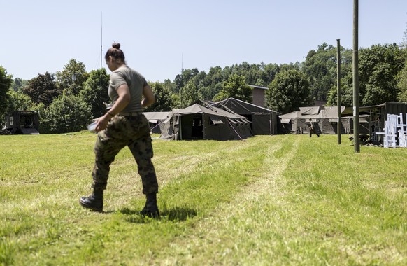 A female soldier walks over a meadow, pictured on site of the medical corps of the Swiss Armed Forces on June 18, 2013, in Buetschwil, canton of St. Gallen, Switzerland. A medical unit of the army run ...