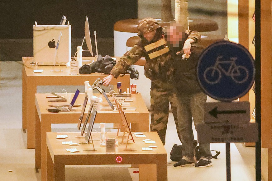 epa09777624 A hostage-taker (L) puts his arm over the shoulder of the hostage (R) during a robbery at the Apple Store on Leidseplein in Amsterdam, the Netherlands, 22 February 2022. The police are pre ...