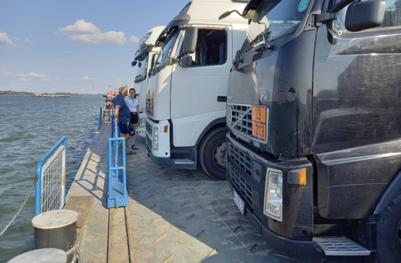 Une femme et un camionneur patientent sur une barge en direction de l&#039;Ukraine. Piétons et voitures de particuliers y jouxtent les poids lourds.