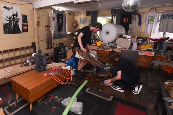 epa11954728 Neighbors clean up a house after floodwaters receded in Oxley, Brisbane, Australia, 11 March 2025. Cyclone Alfred was downgraded to a tropical low but its impact was being felt in a region ...