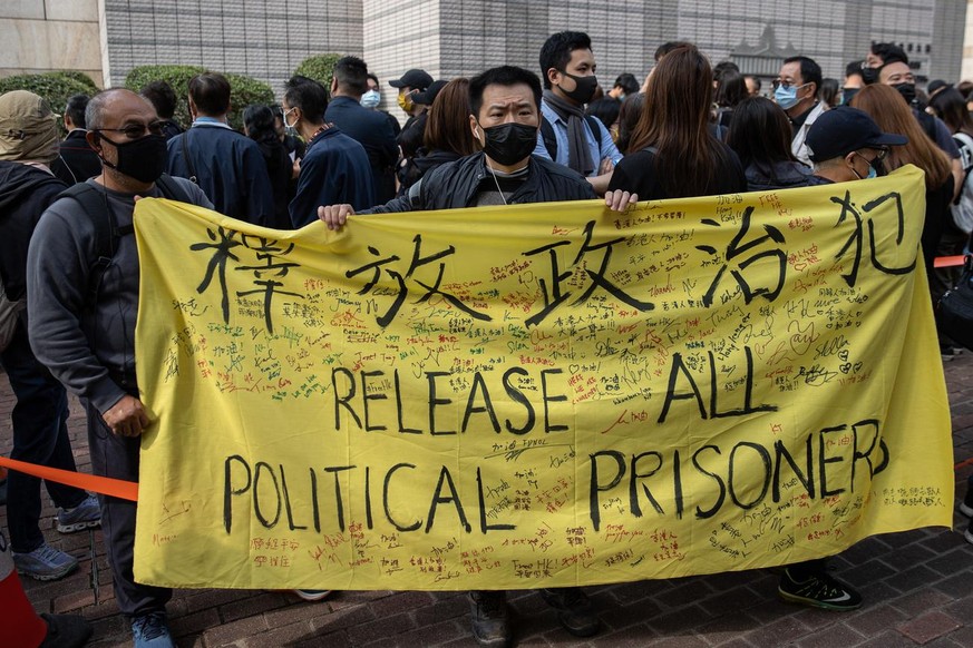 epa09043856 Pro-democracy activists hold banners in support of arrested fellow activists outside the West Kowloon Court in Hong Kong, China, 01 March 2021. Police have charged 47 pro-democracy activis ...