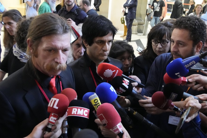 Eagles of Death Metal singer Jesse Hughes, left, and guitarist Eden Galindo, center, answer reporters outside the special court room, Tuesday, May 17, 2022 in Paris. Performers from rock band Eagles o ...