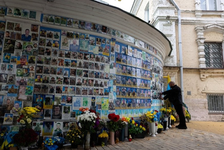 Le nombre de morts ne cesse d&#039;augmenter en Ukraine. Ici, un homme touche la photo de son camarade décédé sur le Mur du souvenir des soldats tombés pour l&#039;Ukraine à Kiev.