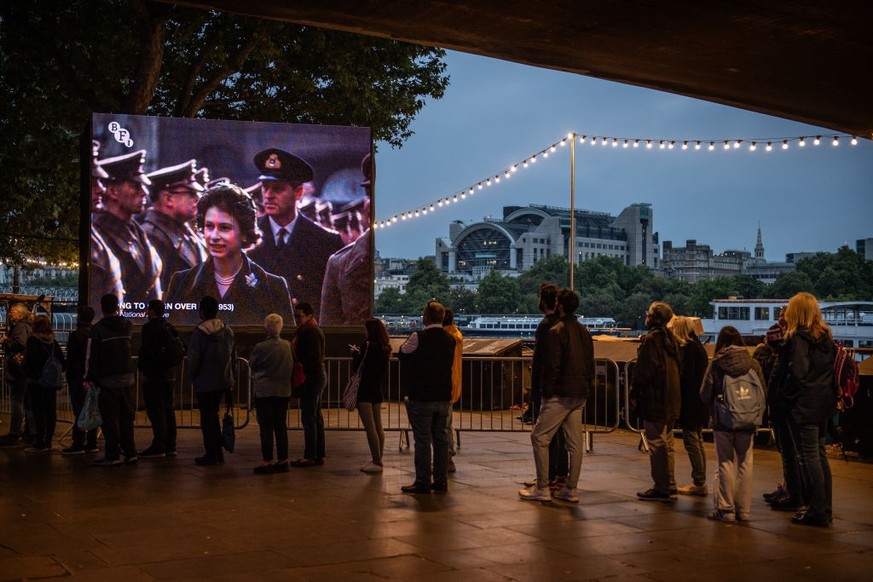 LONDON, ENGLAND - SEPTEMBER 15: An outdoor screen on Southbank plays a film about Queen Elizabeth II&#039;s coronation as well-wishers stand in the queue along Southbank for the Lying-in State of Quee ...