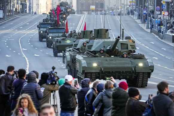 Spectators watches as a Russian T-14 Armata tank, foreground, and other armored vehicles roll along Tverskaya street toward Red Square to attend a rehearsal for the Victory Day military parade in Mosc ...