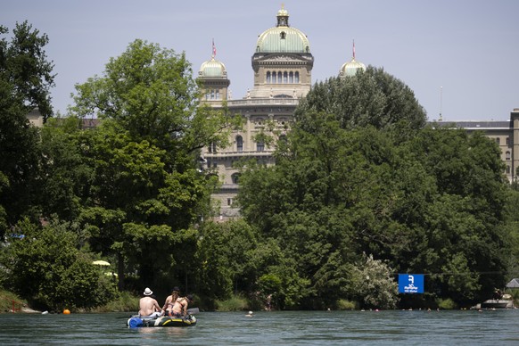 Menschen fahren mit einem Gummiboot auf der Aare am Bundeshaus vorbei, an einem heissen tag, am Samstag, 14. Juni 2025 in Bern. (KEYSTONE/Anthony Anex)